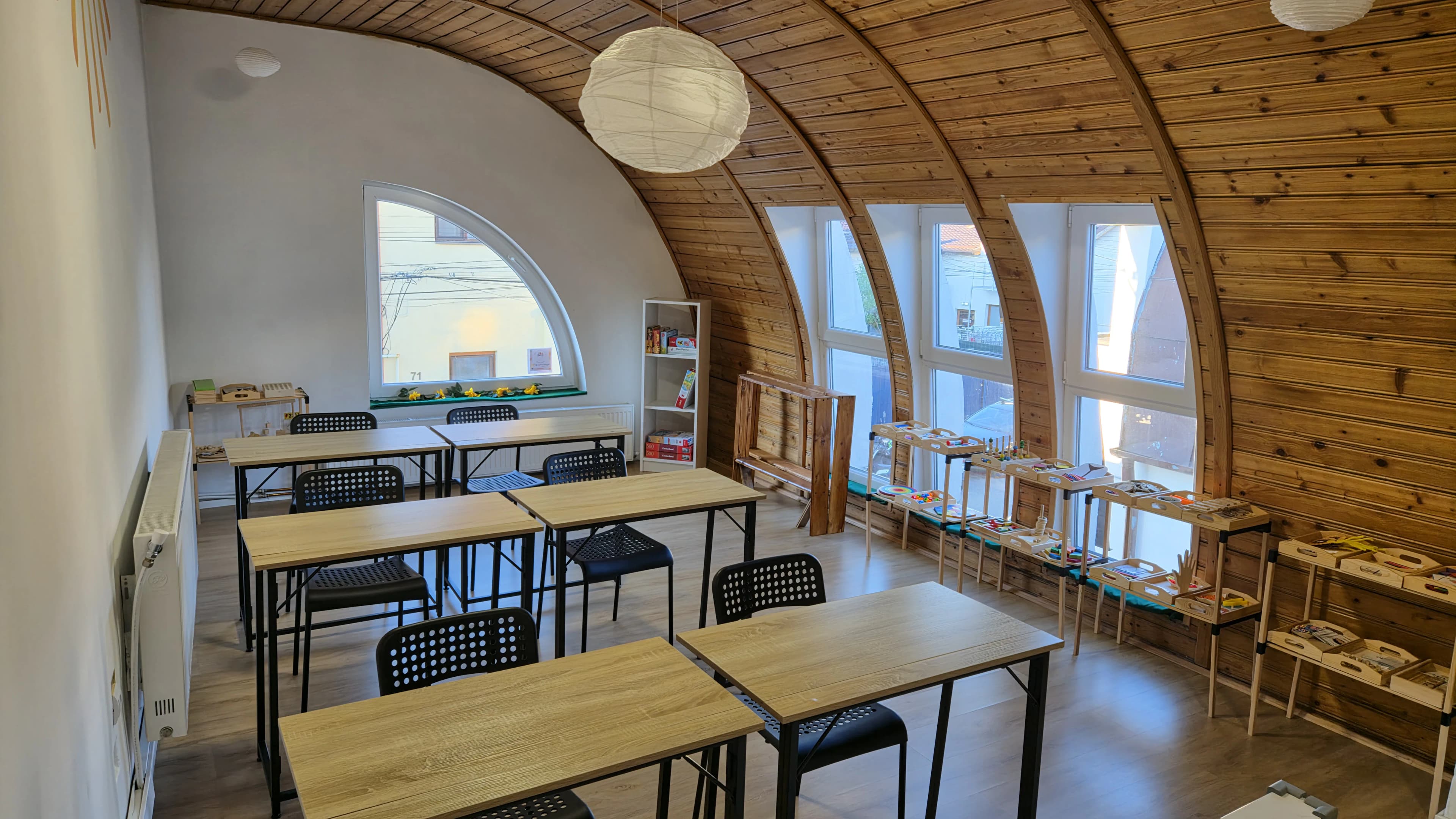 Mese de lucru și un raft cu jocuri educative în sala de after-school